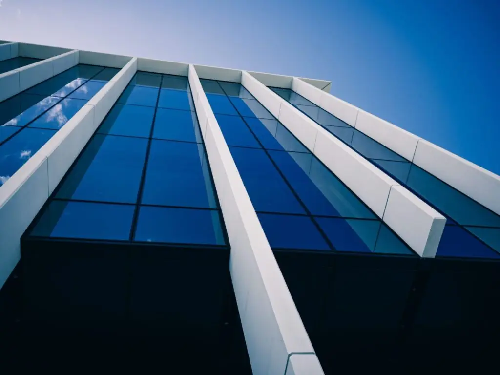 Low-angle view of a modern glass building against a clear blue sky, showcasing bold architectural lines.